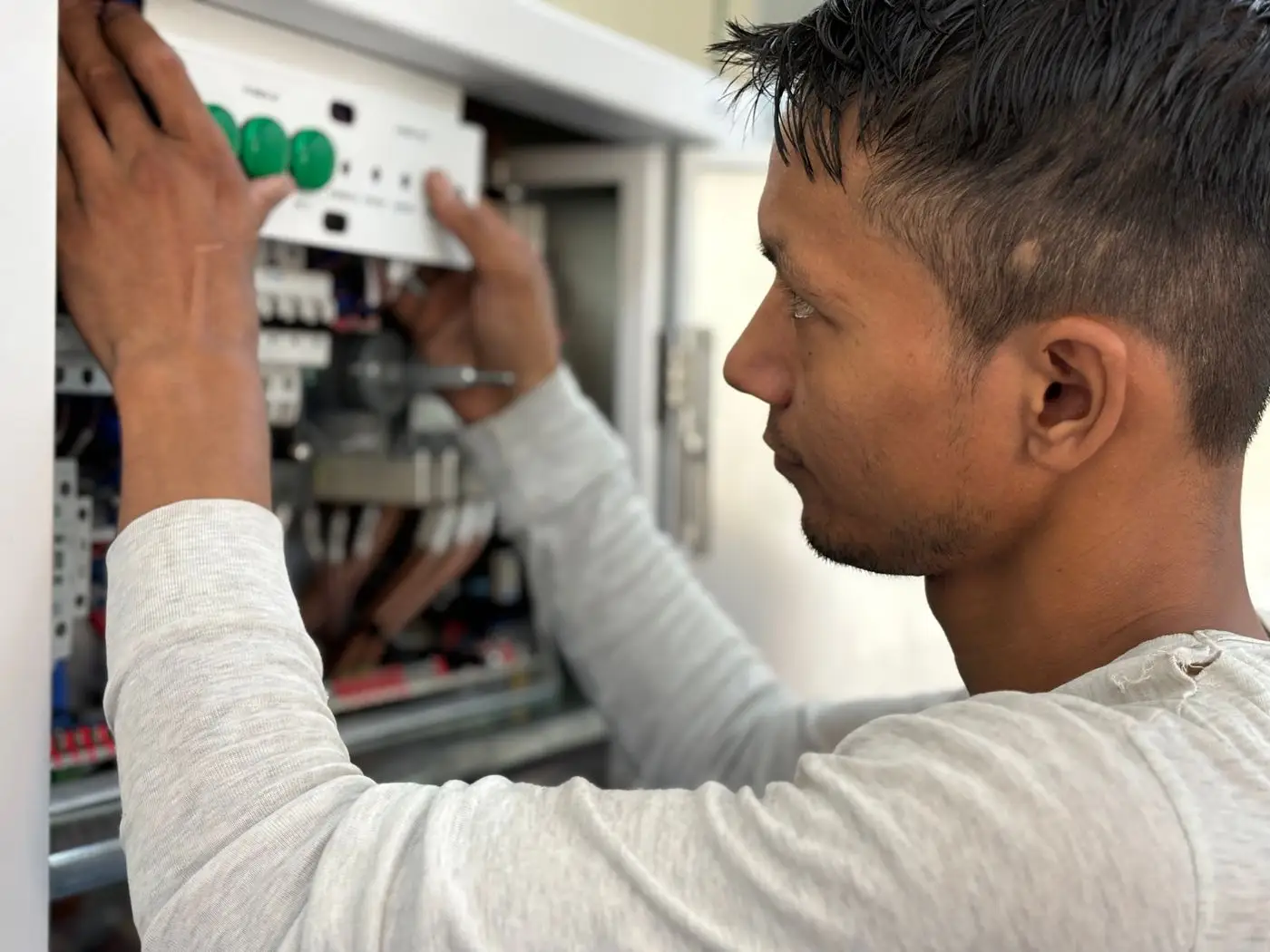 An electrician working on an open electrical panel