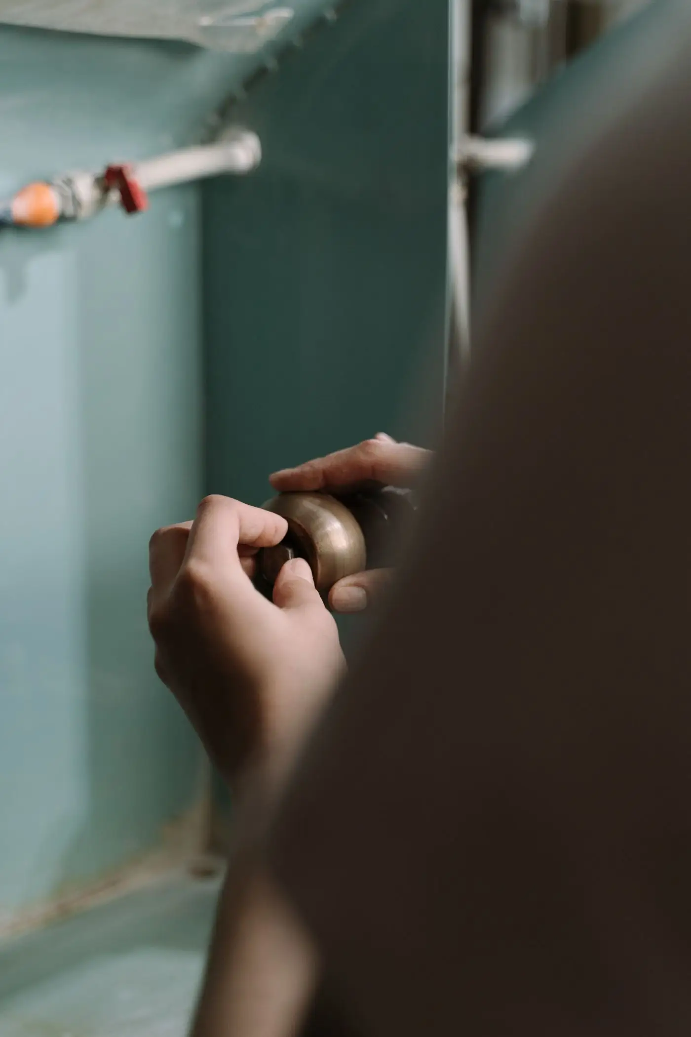 Close-up of hands tightening a pipe fitting under a kitchen sink
