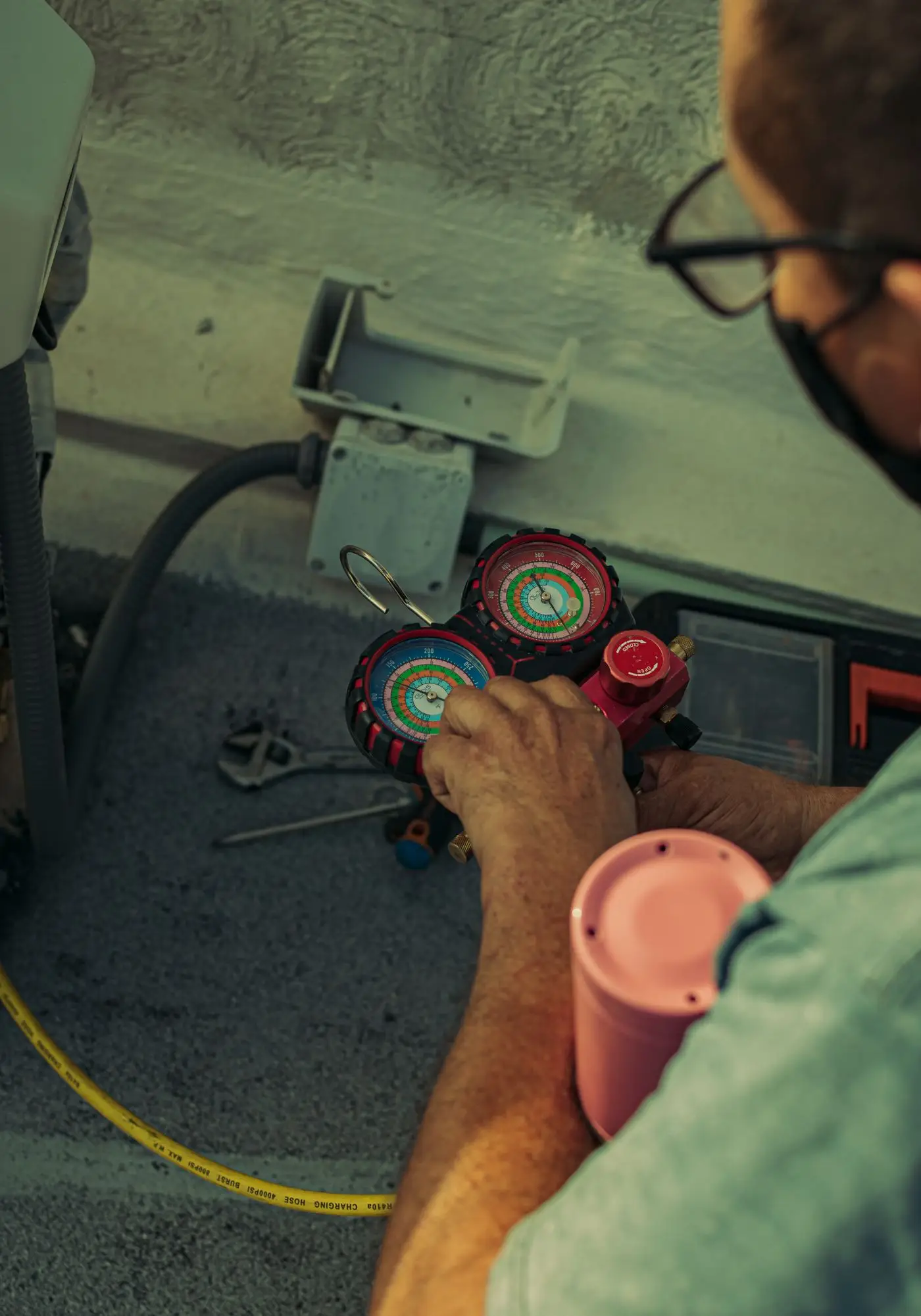 A technician adjusting a refrigerant manifold gauge during air conditioning maintenance