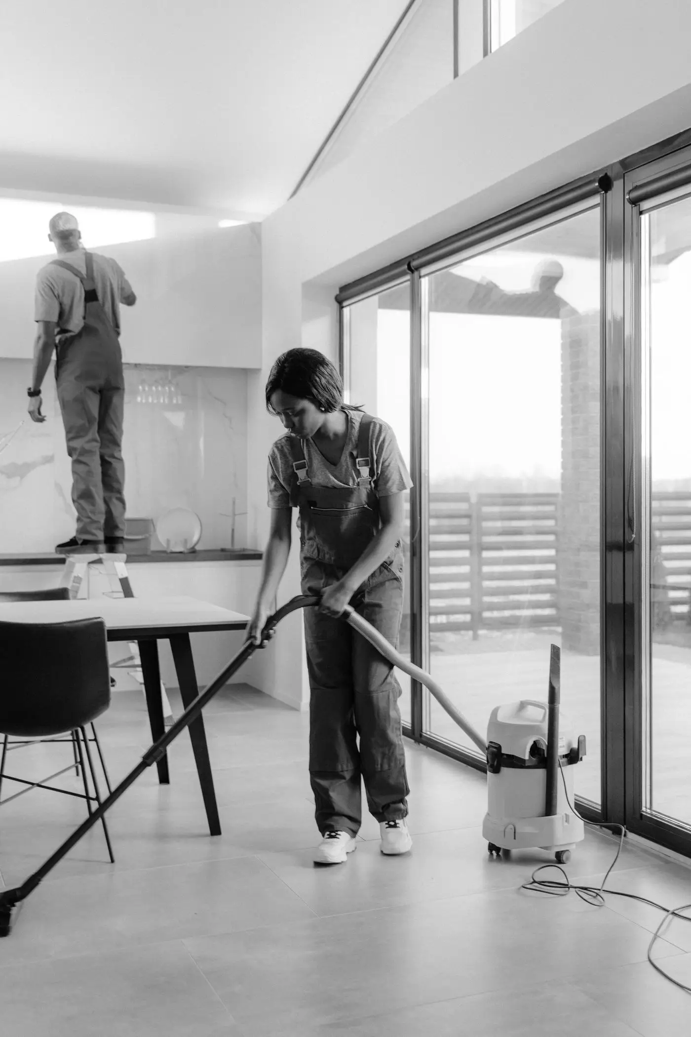 Two professional cleaners vacuuming and dusting a customer's home