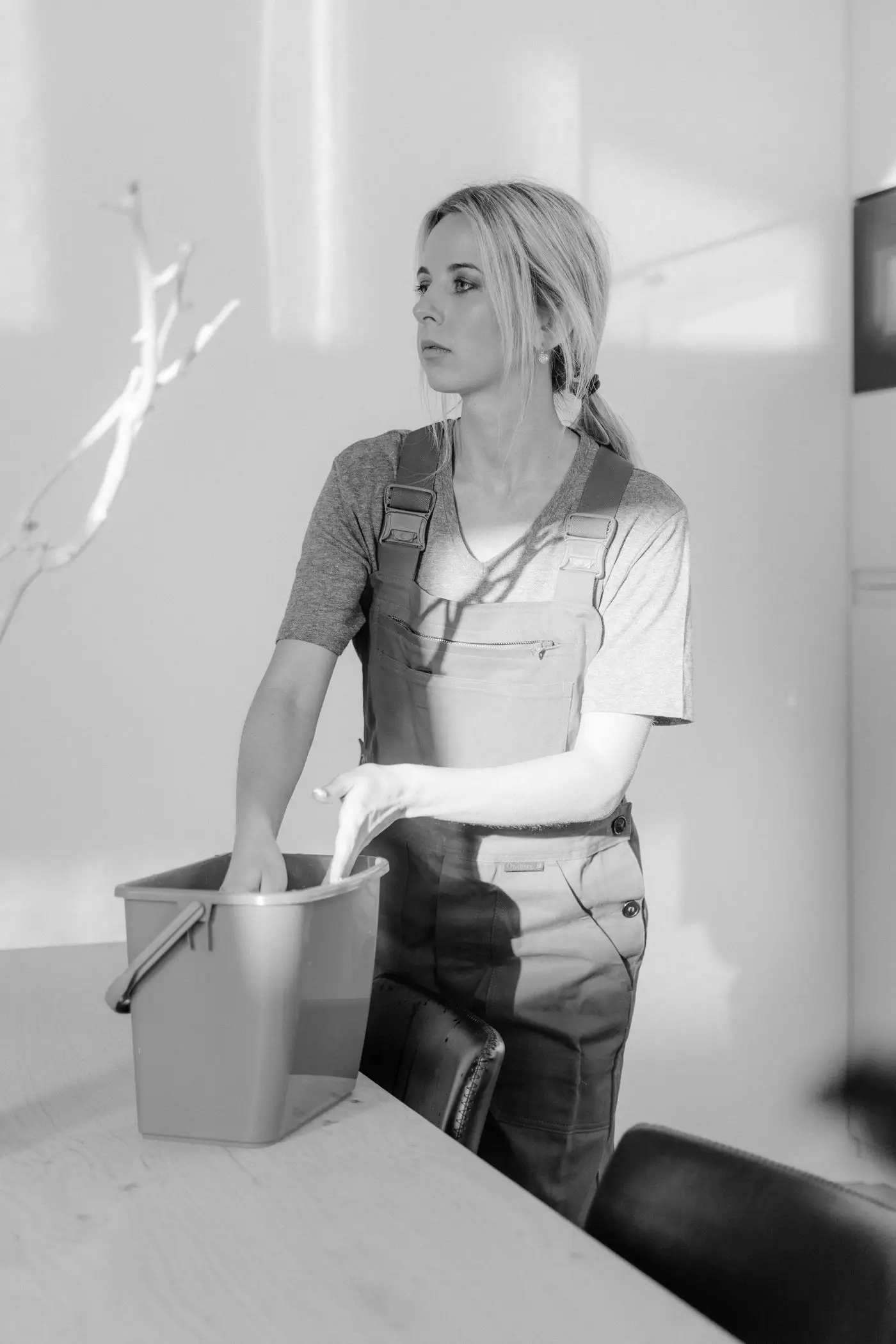 A cleaner in overalls carrying a bucket of supplies