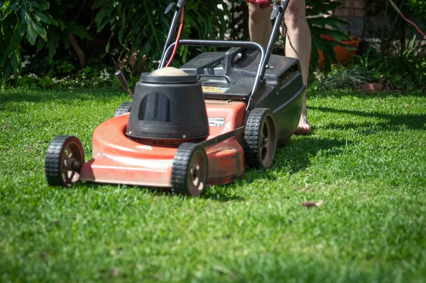 A gardener running a lawn mower over a customer's lawn